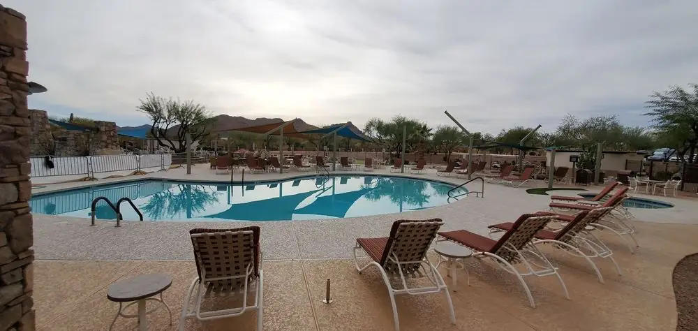 A commercial pool deck finished in cool deck, lounge chairs and shade sails against the Arizona mountains