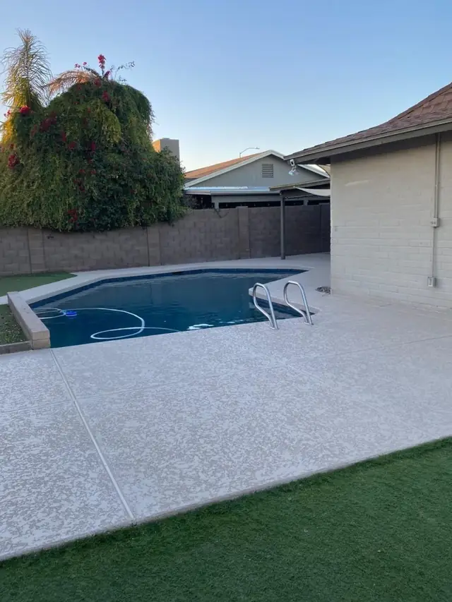 A finished cool deck wrapping a residential Phoenix Valley pool, block wall and bougainvillea behind it